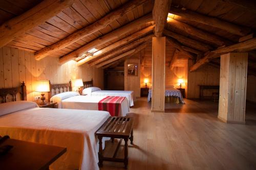 a room with two beds in a building with wooden ceilings at Hotel Novoa in Sarria