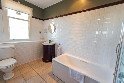 La salle de bains est pourvue d'une baignoire, de toilettes et d'un lavabo. dans l'établissement Nethybridge Hotel, à Nethy Bridge