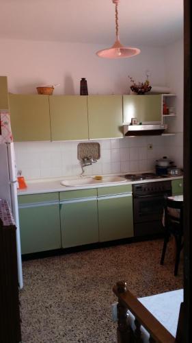 a kitchen with green and white cabinets and a sink at Grigorios Apartments in Nea Vrasna