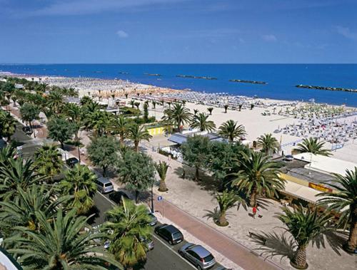a beach with palm trees and a crowd of people at Hotel Imperial in San Benedetto del Tronto