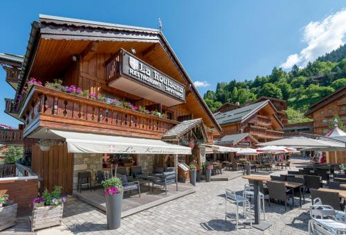 a building with tables and chairs and umbrellas at Hotel Eterlou in Méribel