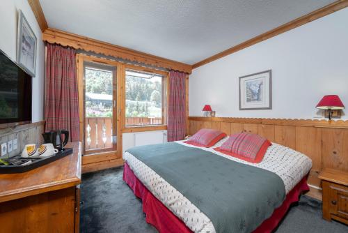 a bedroom with a bed with red pillows and a television at Hotel Eterlou in Méribel