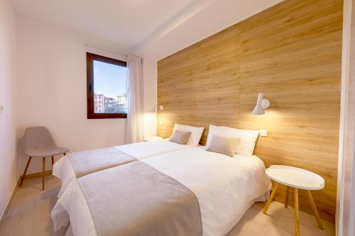 a bedroom with a large white bed with a wooden headboard at Plaza de La Feria Premium Apartments in Las Palmas de Gran Canaria