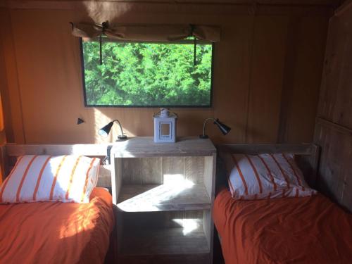 a room with two beds and a table and a window at Glamping Amsterdam "only to be reached by boat" in Baambrugse Zuwe
