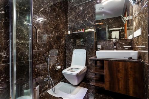 a bathroom with a toilet and a sink and a shower at Atrio by Devam in New Delhi