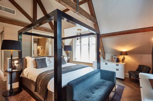 a bedroom with a large canopy bed with a blue chair at Oddfellows On The Park in Cheadle