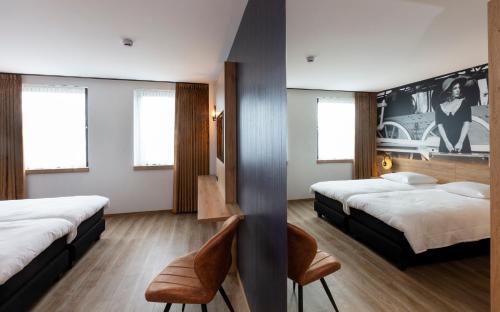 a hotel room with two beds and a chair at Hotel Leo Station, Villa et Annexes in Bastogne