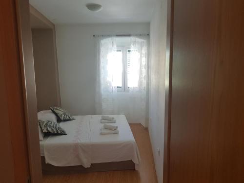 a bedroom with a bed with white sheets and a window at Apartment Central in Šibenik