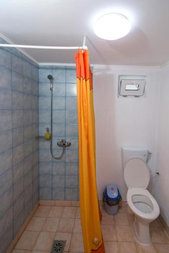 a bathroom with a shower with an orange shower curtain at La Livada in Greci