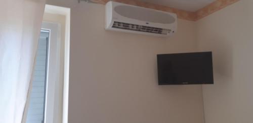 TV de pantalla plana colgada en una pared blanca en La Farfalla, en Fossacesia