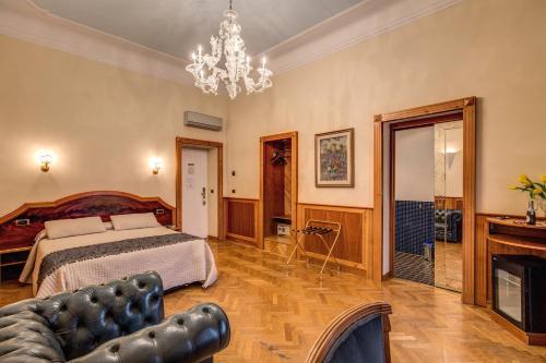una camera con letto, divano e lampadario a braccio di Relais Conte Di Cavour De Luxe a Roma
