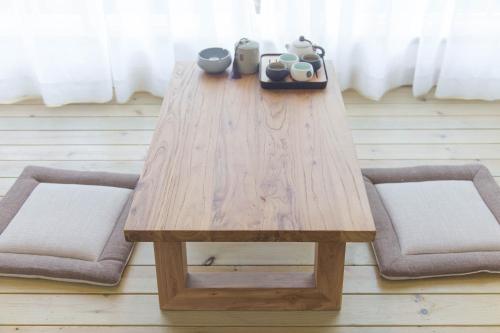 a wooden table with two chairs and a table with cups at Qingcheng Mountain Huakai Shiminsu in Dujiangyan