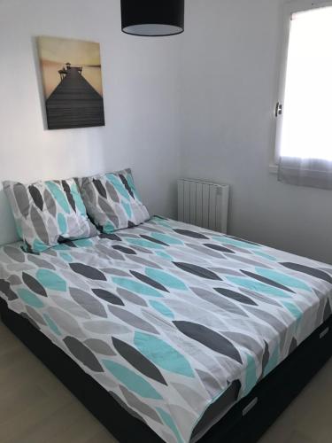 Bett mit Daunendecke in einem Schlafzimmer in der Unterkunft T2 jardinet, accès direct plage in Cabourg