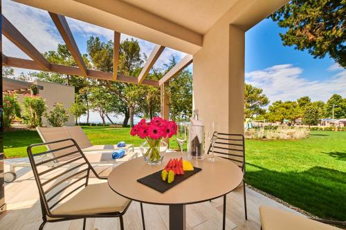 a table with a vase of flowers on a patio at Garden Suites Umag Plava Laguna in Umag