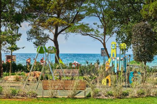 a playground with the ocean in the background at Garden Suites Umag Plava Laguna in Umag