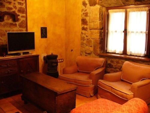 ein Wohnzimmer mit einem TV, einem Sofa und Stühlen in der Unterkunft Alojamientos Casa Luisa in Puertas