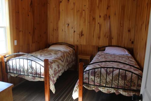 two twin beds in a room with wooden walls at Chalets Grand Pre Cottages in North Rustico