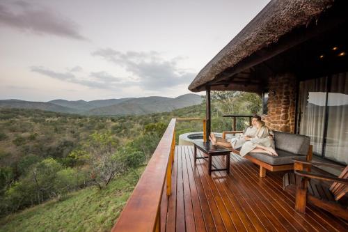 a woman sitting on the deck of a house at Leopard Mountain Safari Lodge in Manyoni Private Game Reserve