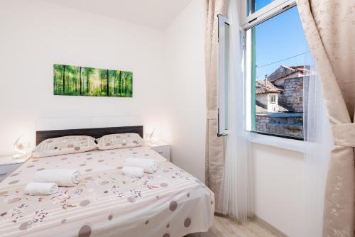 a white bedroom with a bed and a window at Apartment Linda in Split