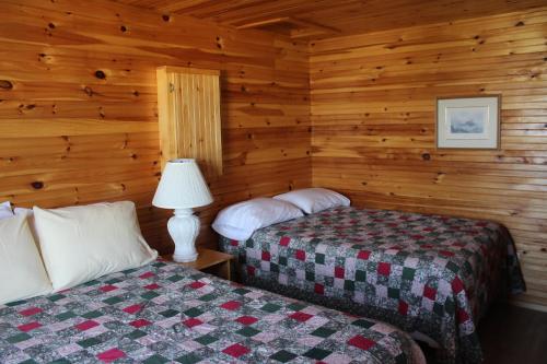 two beds in a room with wooden walls at Chalets Grand Pre Cottages in North Rustico