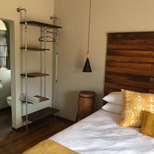 a bedroom with a white bed with a wooden headboard at Blue Rain Guest House in Bloemfontein