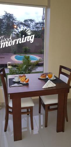 a wooden table with two chairs and a table with food on it at Iguazú Urban Hotel Express in Puerto Iguazú