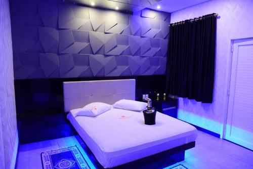 Cette chambre violette comprend un lit avec des draps blancs. dans l'établissement Helus Motel, à Passo Fundo