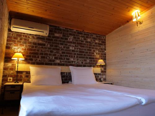 a bedroom with a white bed with a brick wall at Hotel Anchor in Sinemorets