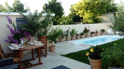 un patio avec une table et des plantes en pot ainsi qu'une piscine dans l'établissement L'Hibiscus Chambre d'Hôte, à Avignon