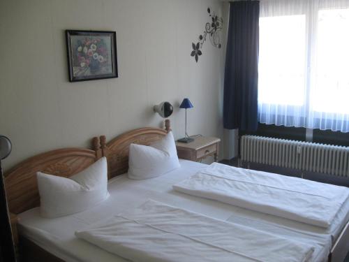 Schlafzimmer mit einem Bett mit weißer Bettwäsche und einem Fenster in der Unterkunft Hotel Garni Central in Triberg