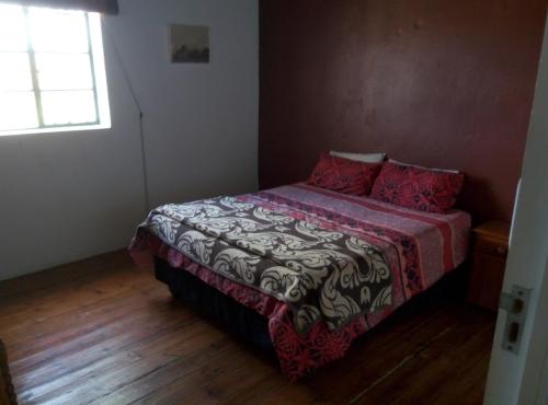 1 dormitorio con 1 cama con manta roja y blanca en Infinity farm, en Riversdale