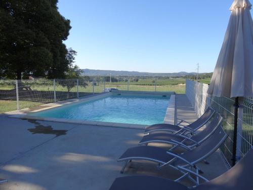 a swimming pool with lounge chairs and an umbrella at La Bastide des Borels in Berrias Et Casteljau