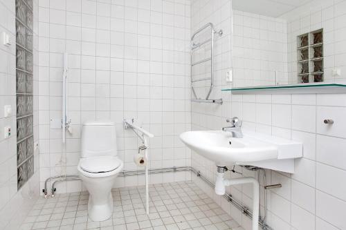 a white bathroom with a toilet and a sink at Hensbacka Herrgård in Munkedal