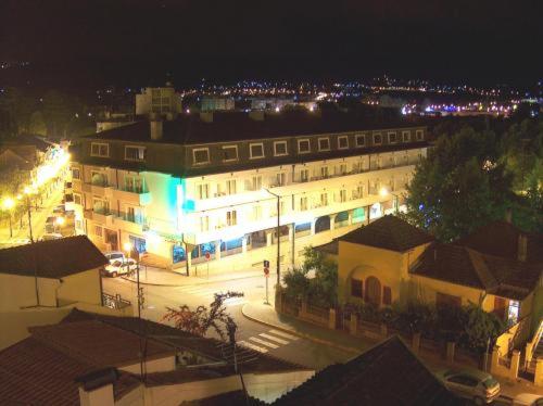 a lit up building with a street at night at Petrus Hotel in Chaves