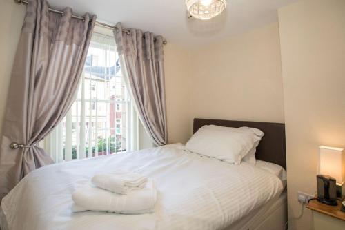 a bedroom with a bed with white sheets and a window at The Royal Oak Pub in Lampeter