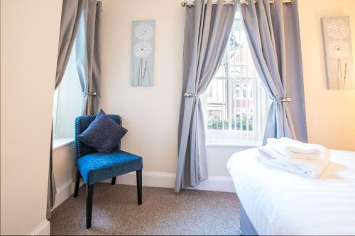 a bedroom with a blue chair in front of a window at The Royal Oak Pub in Lampeter