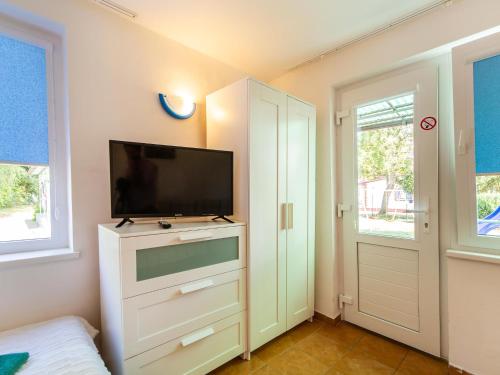 a bedroom with a flat screen tv on a dresser at Domki letniskowe Wiga in Kołobrzeg