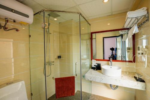 een badkamer met een douche, een wastafel en een spiegel bij Le Bordeaux Sapa Hotel in Sa Pa