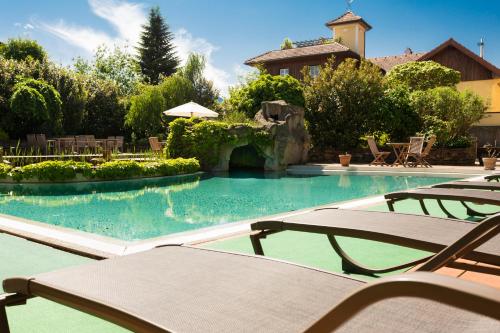 a swimming pool with two chairs and a house at Boutique Hotel Aichinger in Nussdorf am Attersee