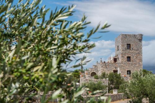 un antiguo edificio de piedra con árboles en primer plano en Charouda Stone Tower, en Pyrgos Dirou