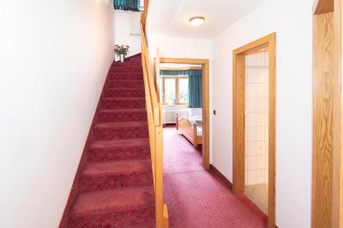 a red carpeted staircase in a room with a red carpet at Kirchenwirt in Reith im Alpbachtal