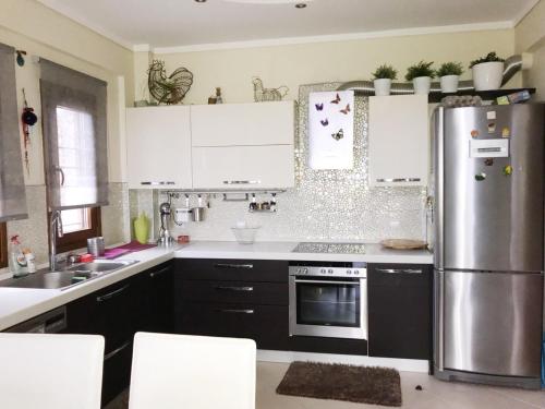 a kitchen with white cabinets and a stainless steel refrigerator at Seafront house with garden in Ierissos
