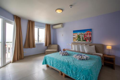 a bedroom with a bed and a chair and windows at Blue Bay Apartments in Sint Michiel
