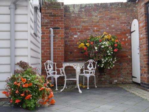 a patio with two white chairs and flowers at Panfield House in Braintree