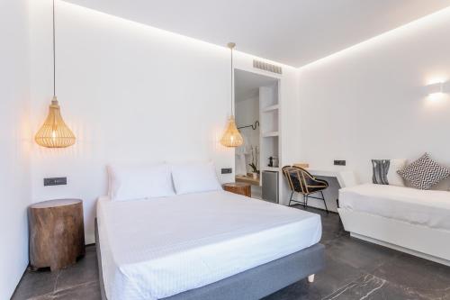 a white bedroom with a bed and a chair at Aegean Gem in Kamari