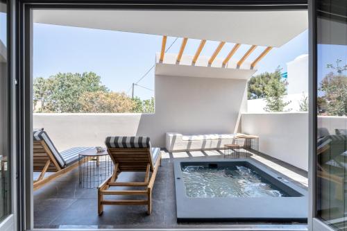 eine Terrasse mit einem Whirlpool, einem Tisch und Stühlen in der Unterkunft Aegean Gem in Kamari