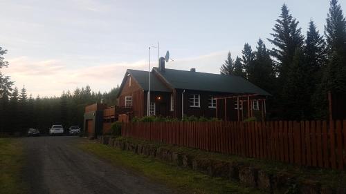 een huis met een hek naast een onverharde weg bij Guesthouse Grai Hundurinn in Hallormsstaður