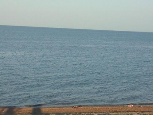 a large body of water with a person walking on the beach at Гостевой дом Сафар in Kapchagay