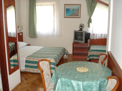 a room with two beds and a table and a television at Apartments Mladina in Mimice