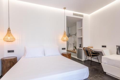 a white bedroom with a bed and a chair at Aegean Gem in Kamari